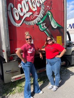 Ashley and Jill standing in front of a Coca-Cola Semi Truck.